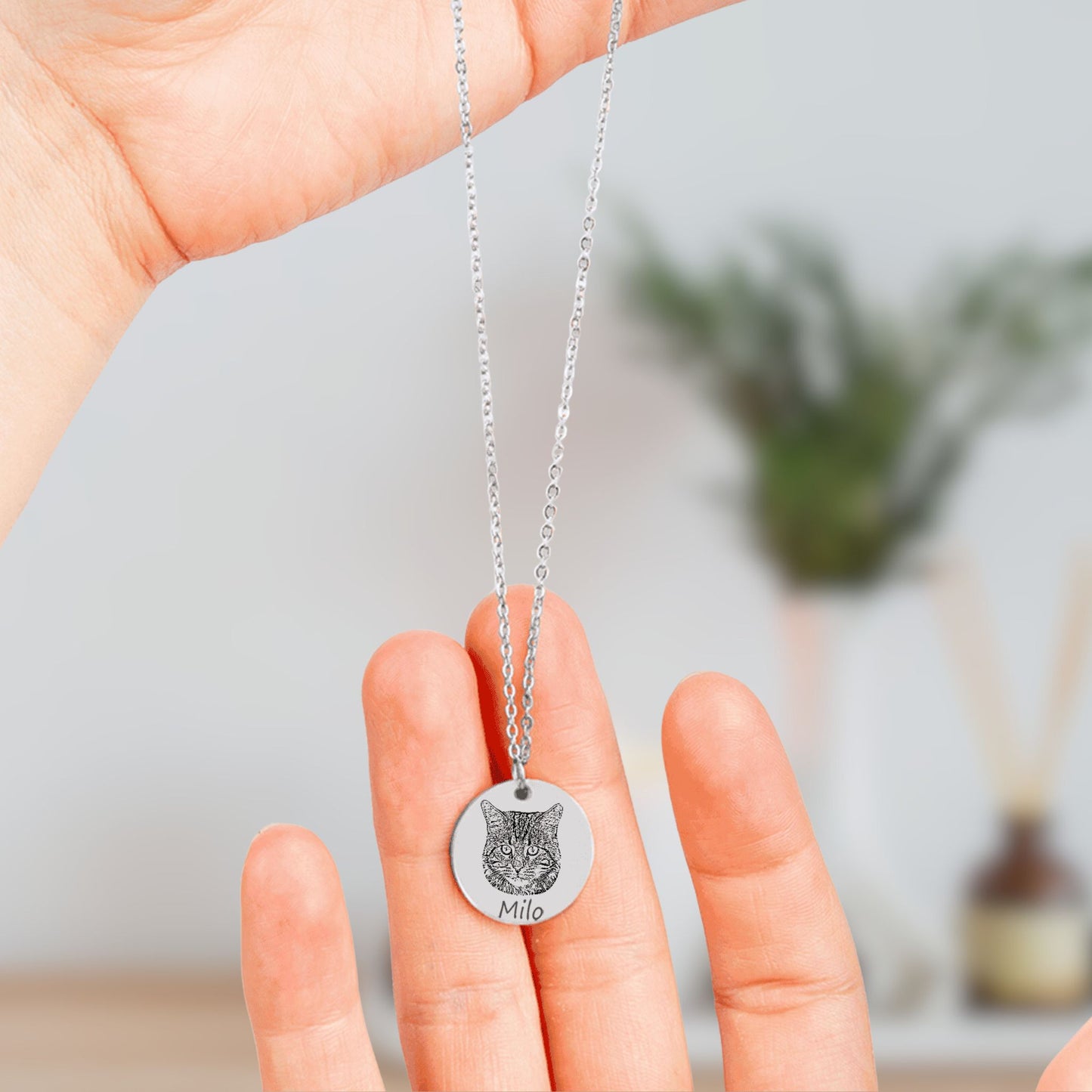 personalized cat picture necklace in silver held in hands