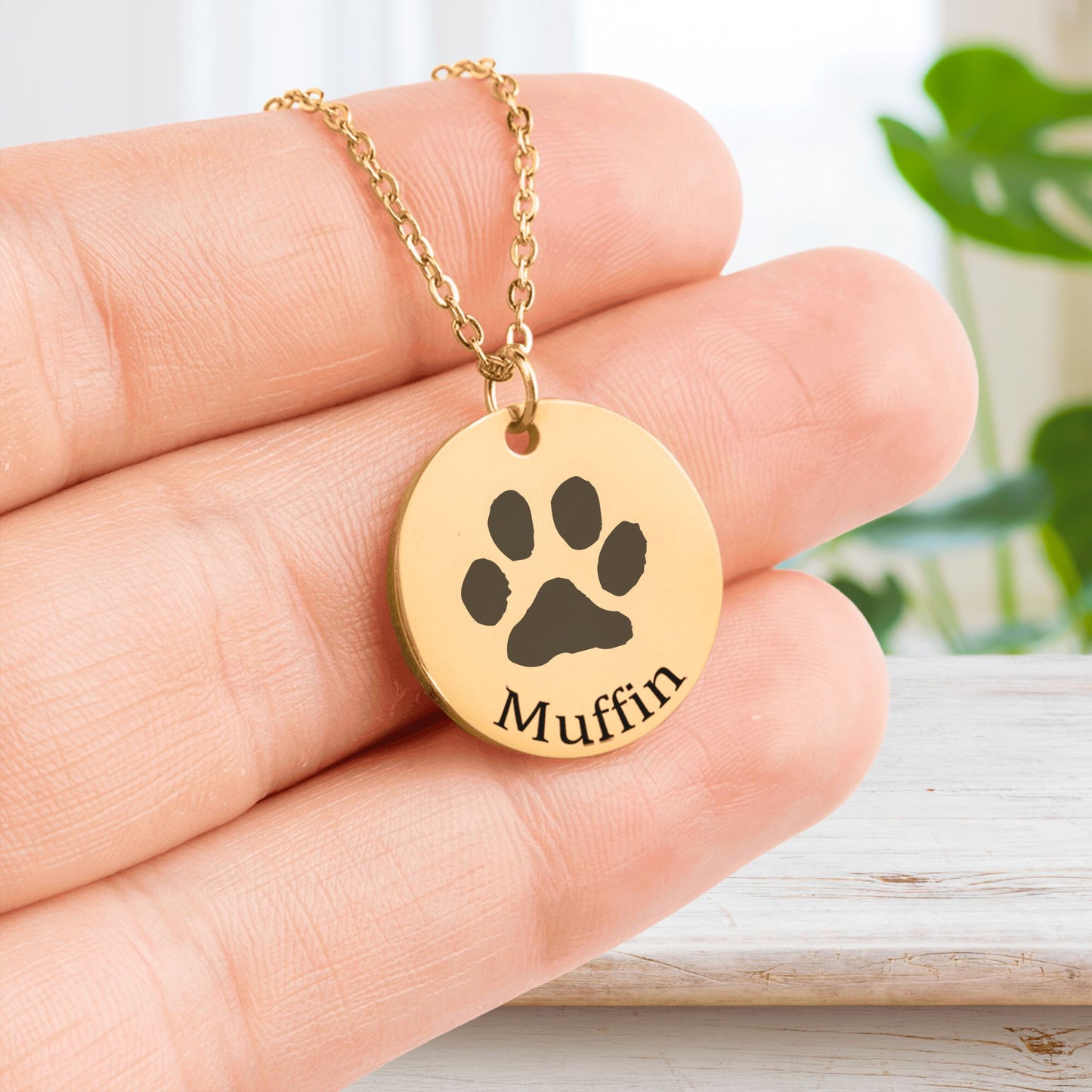 custom paw print necklace in gold held in a hand