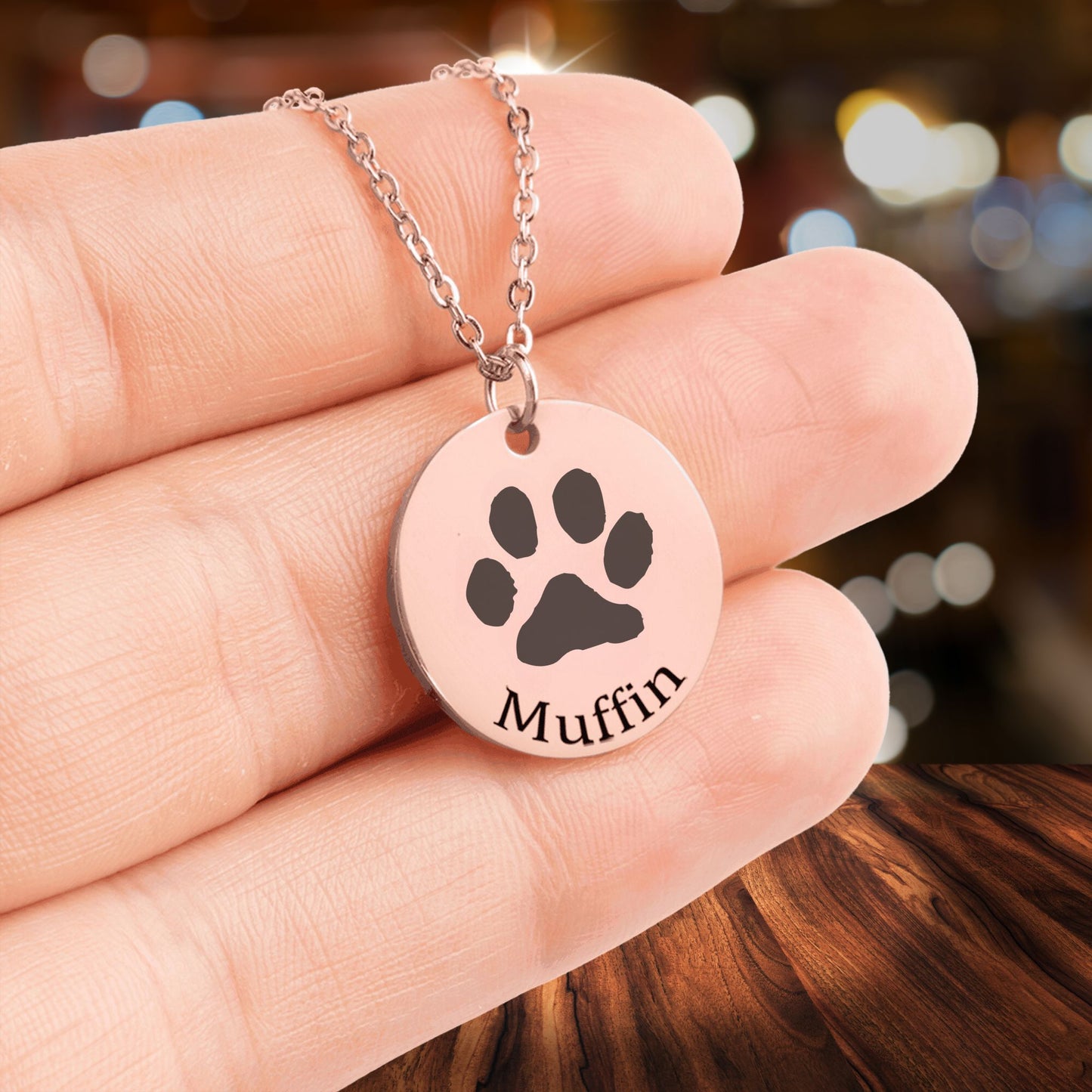personalized paw print necklace in rose gold held in a hand