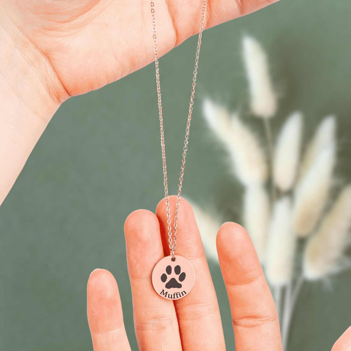 personalized paw print necklace in rose gold held in hands