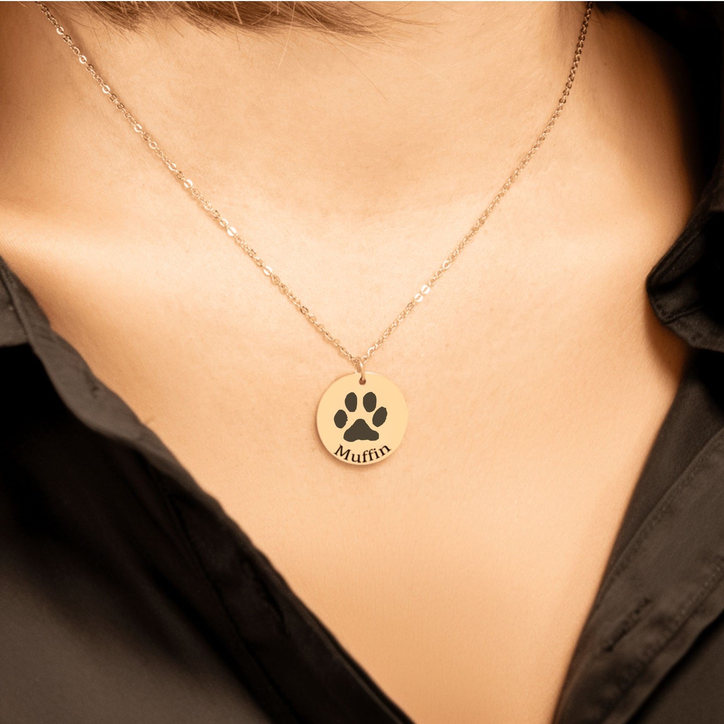 custom pet paw print necklace in gold worn by a woman in a black shirt
