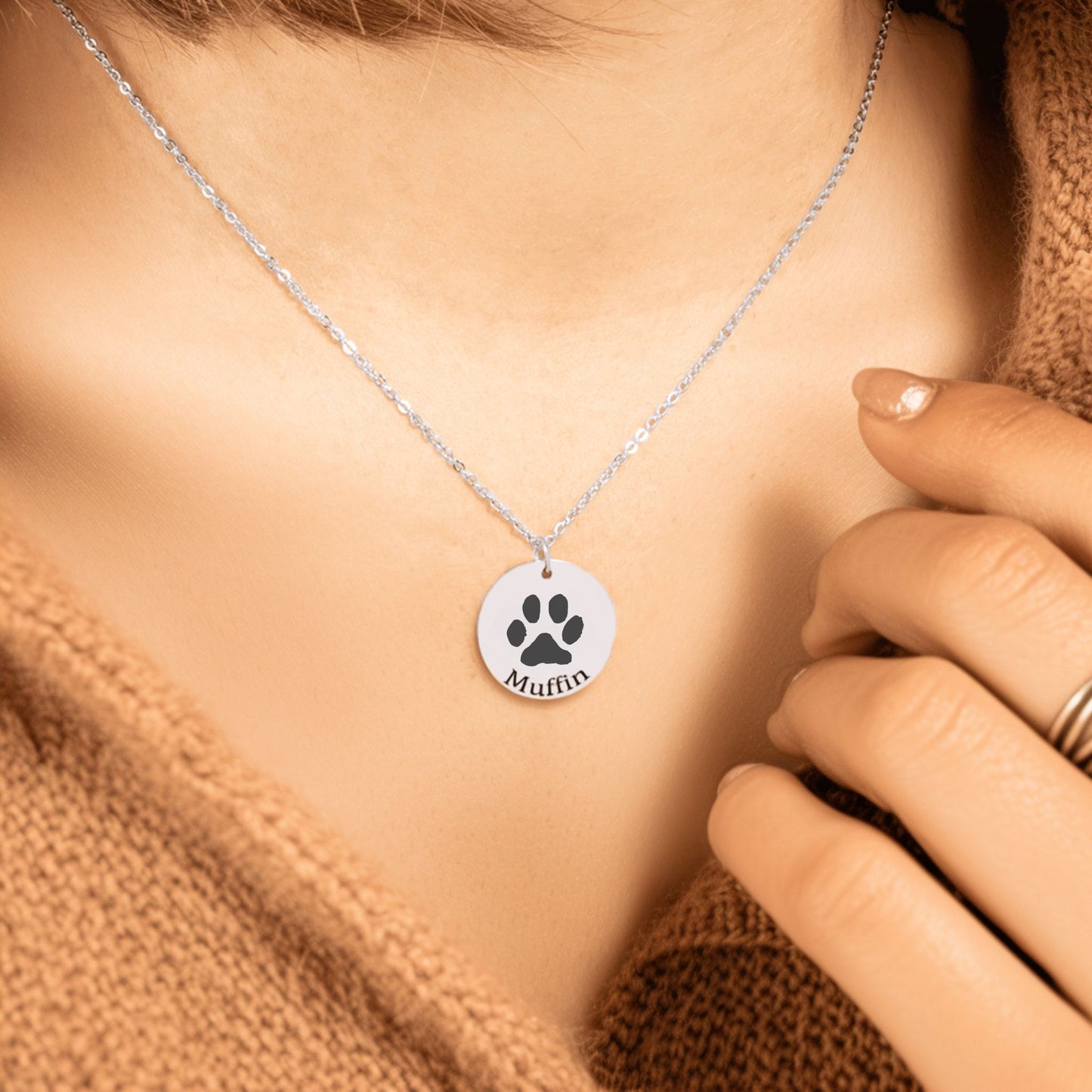personalized pet paw print necklace in silver worn by a woman in a taupe sweater