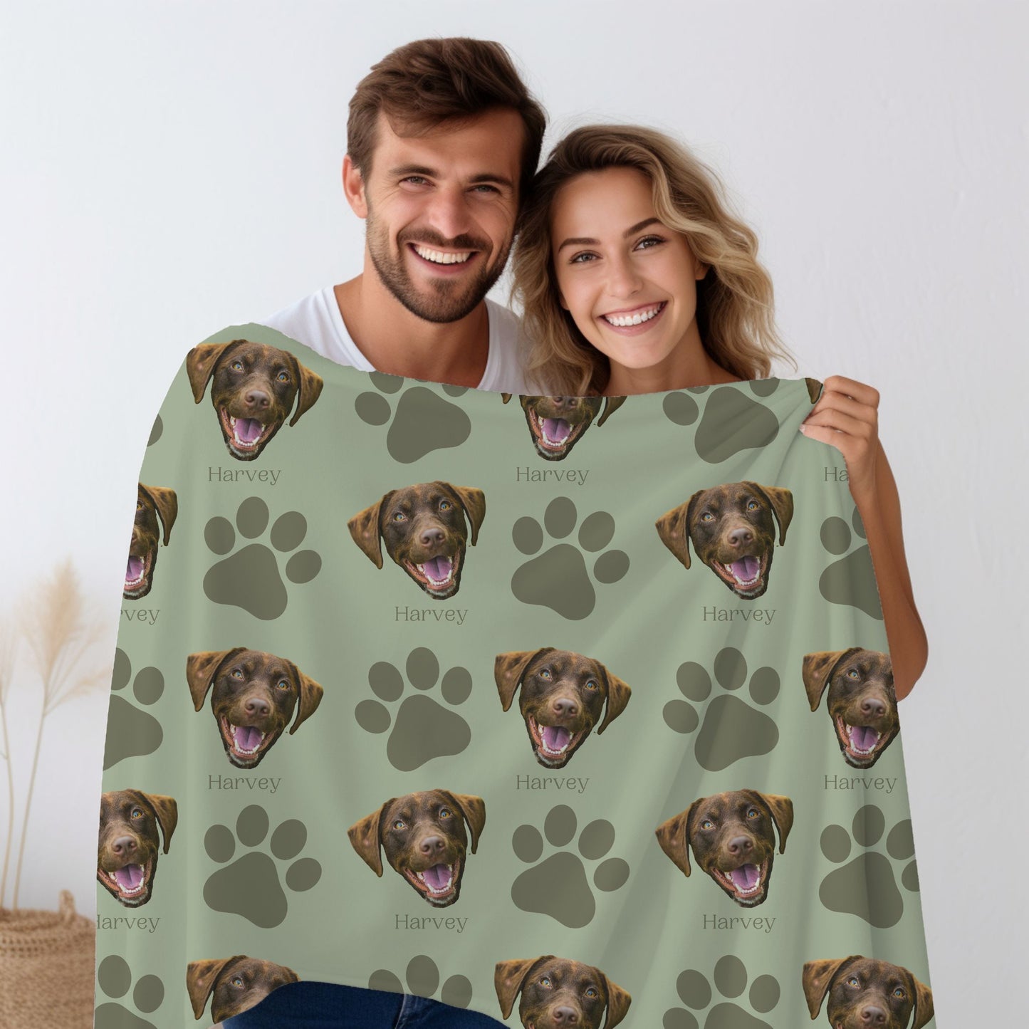 a man and woman holding a custom dog face photo blanket in olive/sage